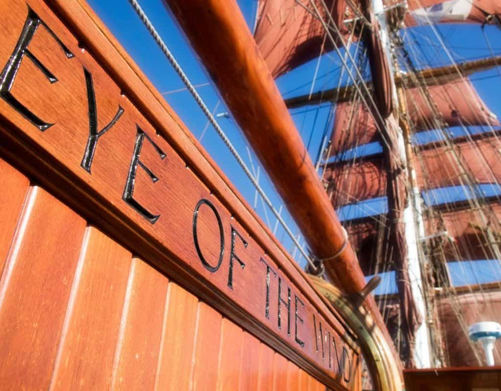 Tallship eye of the wind wooden nameplate with the square sails in the background. Adventure sailing holidays with classic sailing