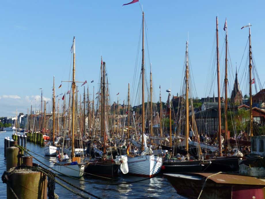 A crowd of traditional sailing ships rafted up together in the historic German town of Flensburg for the annual Rum Regatta